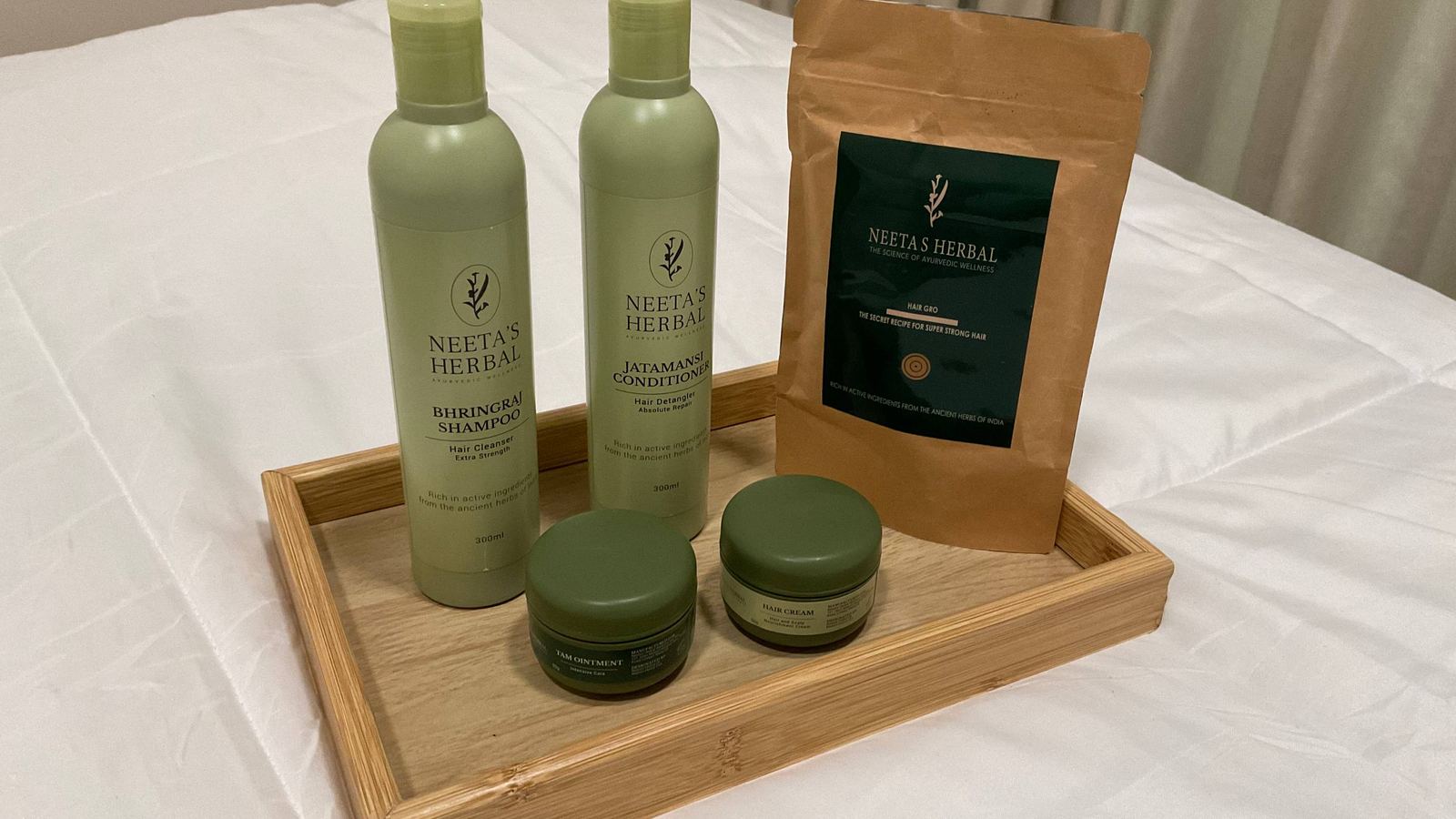 Neeta's Herbal shampoo, conditioner, hair powder and two creams on a wooden tray in the studio.