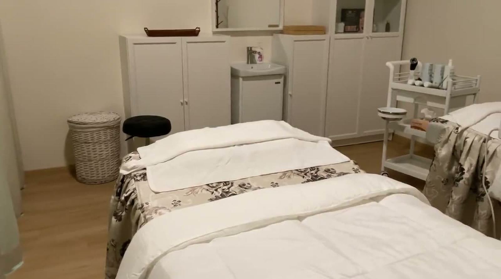 The treatment room at Vajra Sree Beauty: two facial beds made up with white towels and quilts.